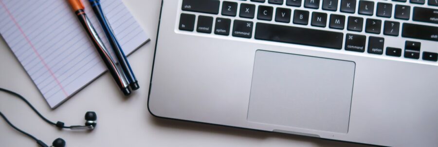 silver laptop computer beside white ruled paper